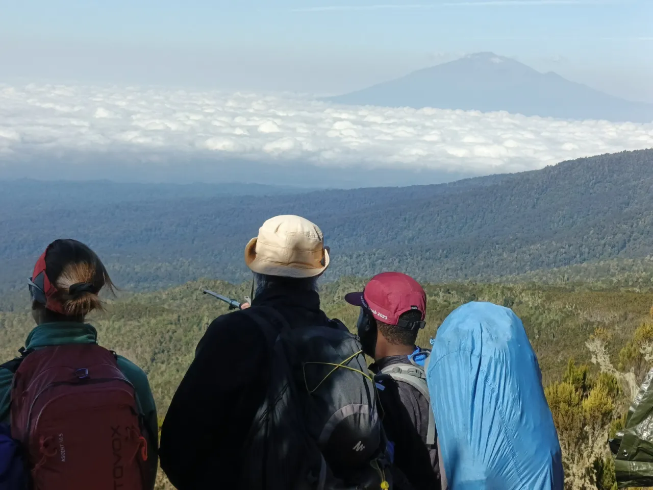 Climbers looking across a sea of cloud towards the peak of Mount Meru